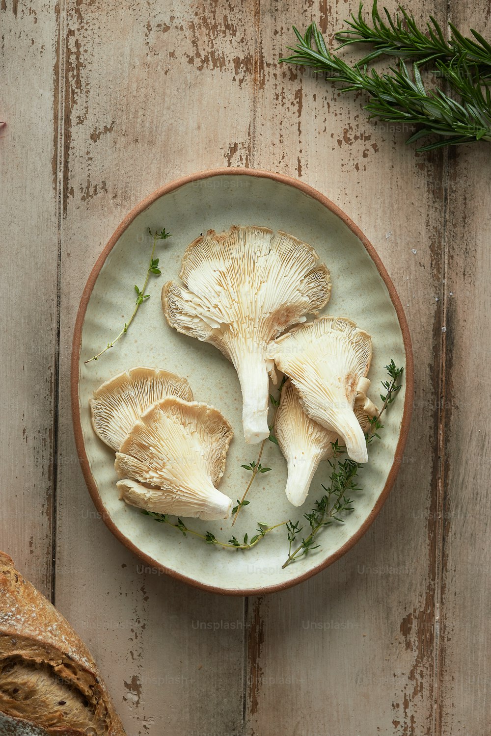빵 한 덩어리 옆에 버섯을 얹은 흰색 접시