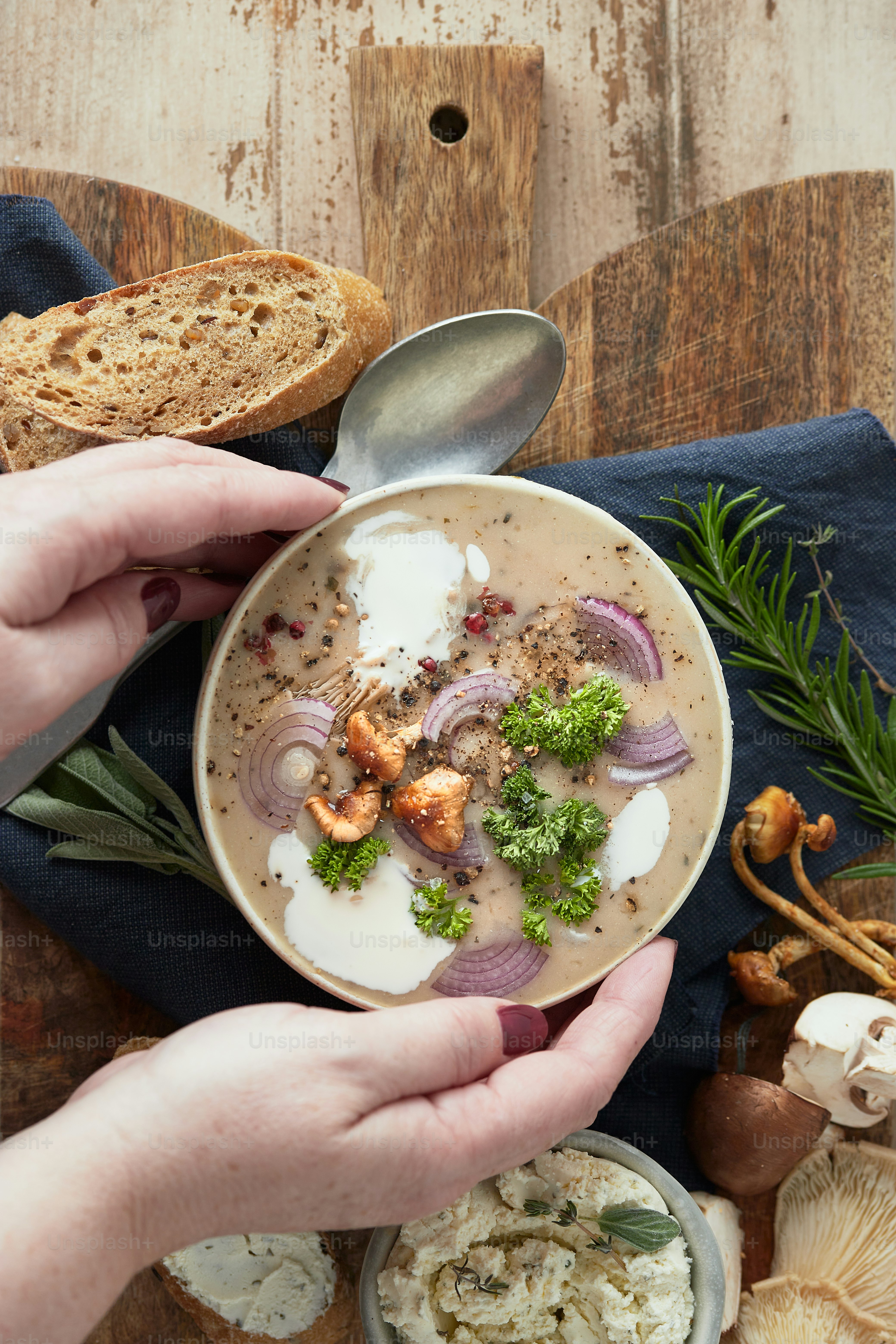 eine Person, die eine Schüssel Suppe auf einem Holztisch hält
