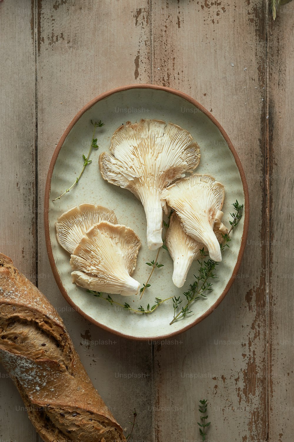 a white plate topped with mushrooms next to a loaf of bread