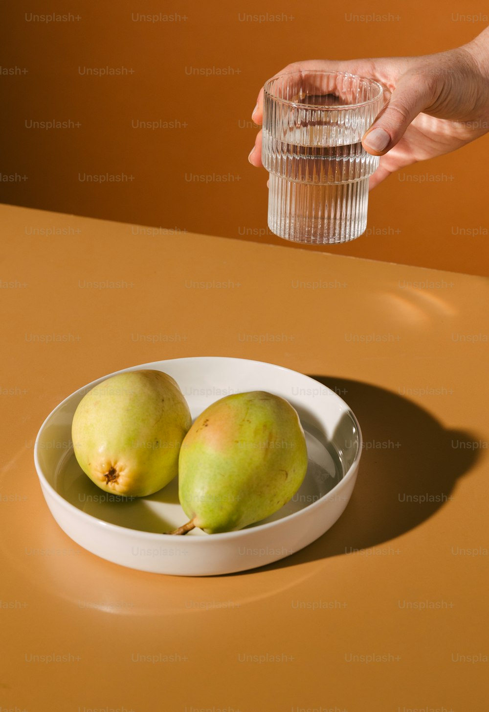 a bowl of fruit on a table with a glass of water