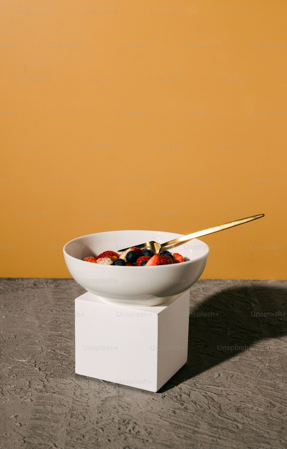 a bowl of fruit with a gold spoon in it