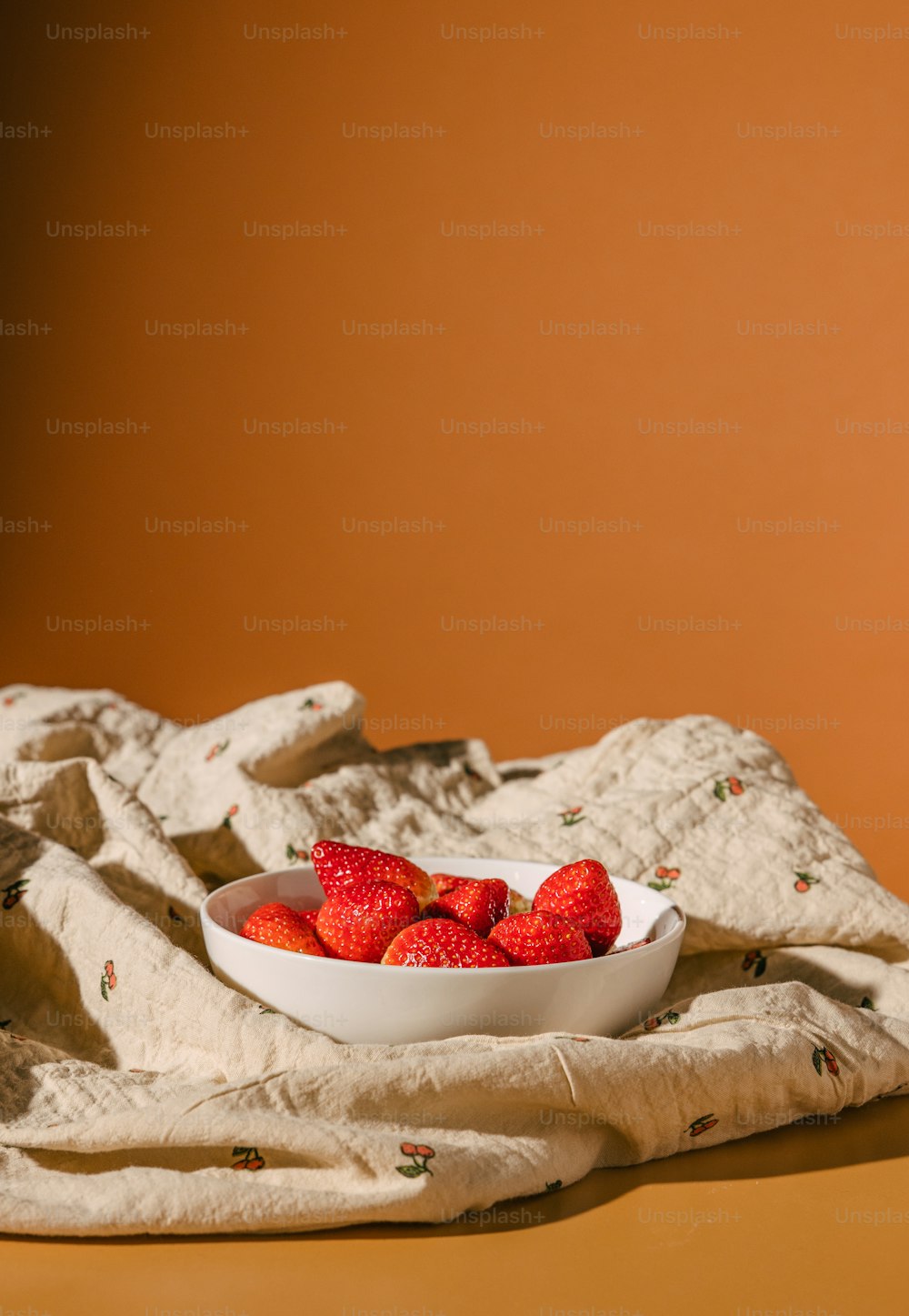 a bowl of strawberries is sitting on a towel