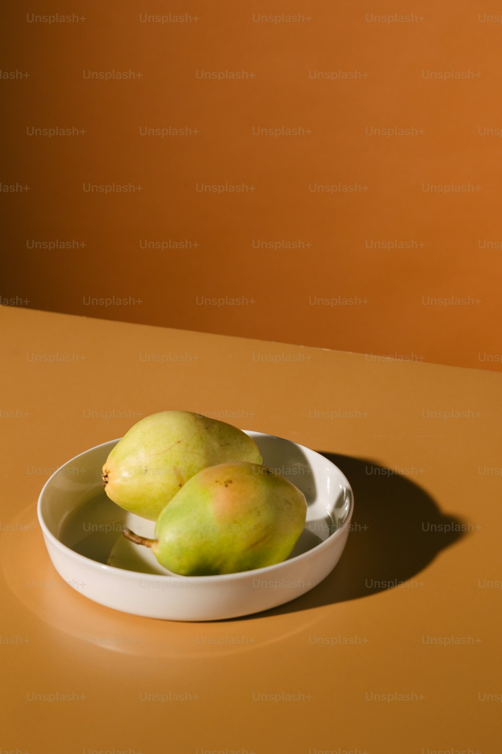 uma tigela branca cheia de frutas verdes em cima de uma mesa
