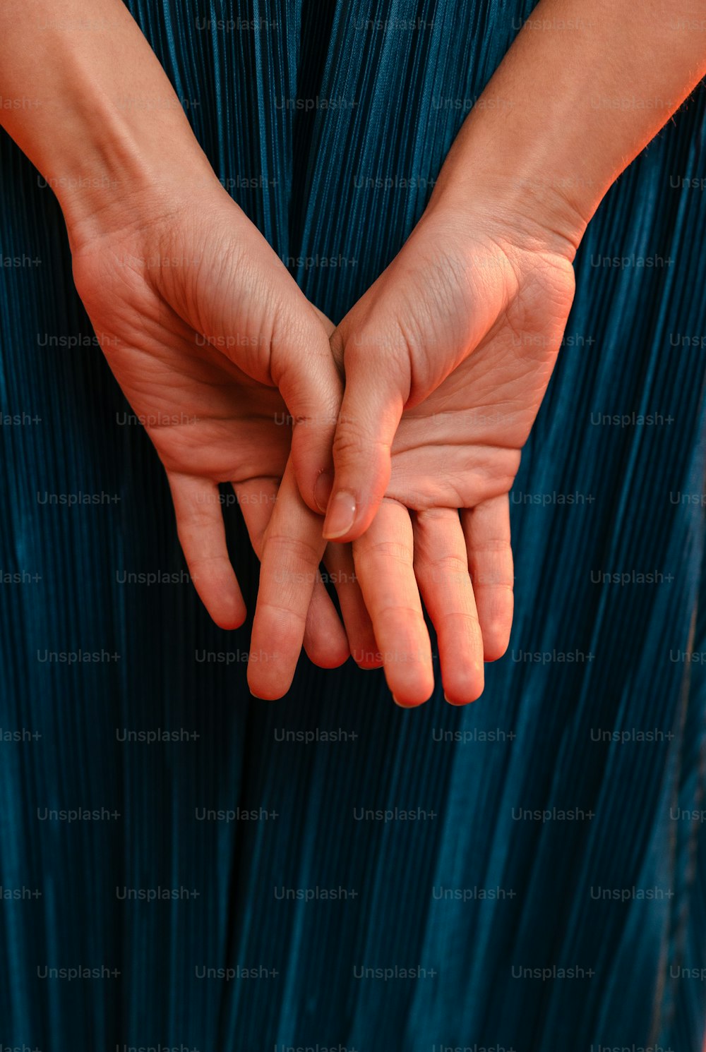uma mulher em um vestido azul segurando suas mãos juntas
