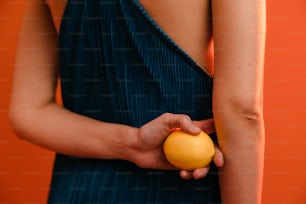 Una mujer con un vestido azul sosteniendo una naranja