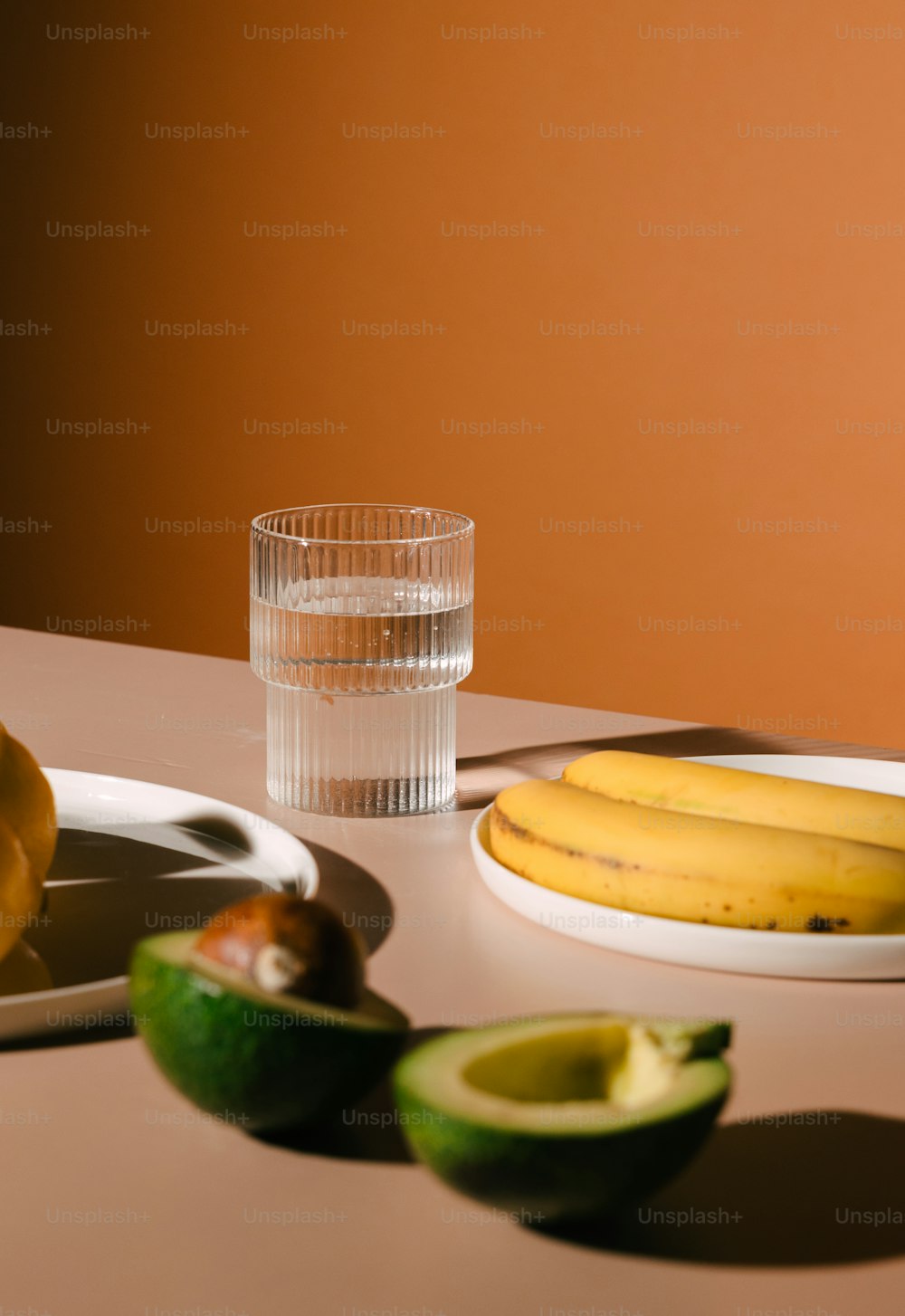 a table with a plate of fruit and a glass of water