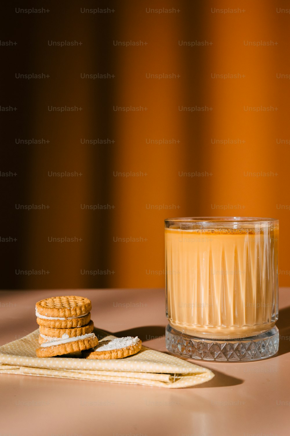 a glass of orange juice next to a stack of cookies