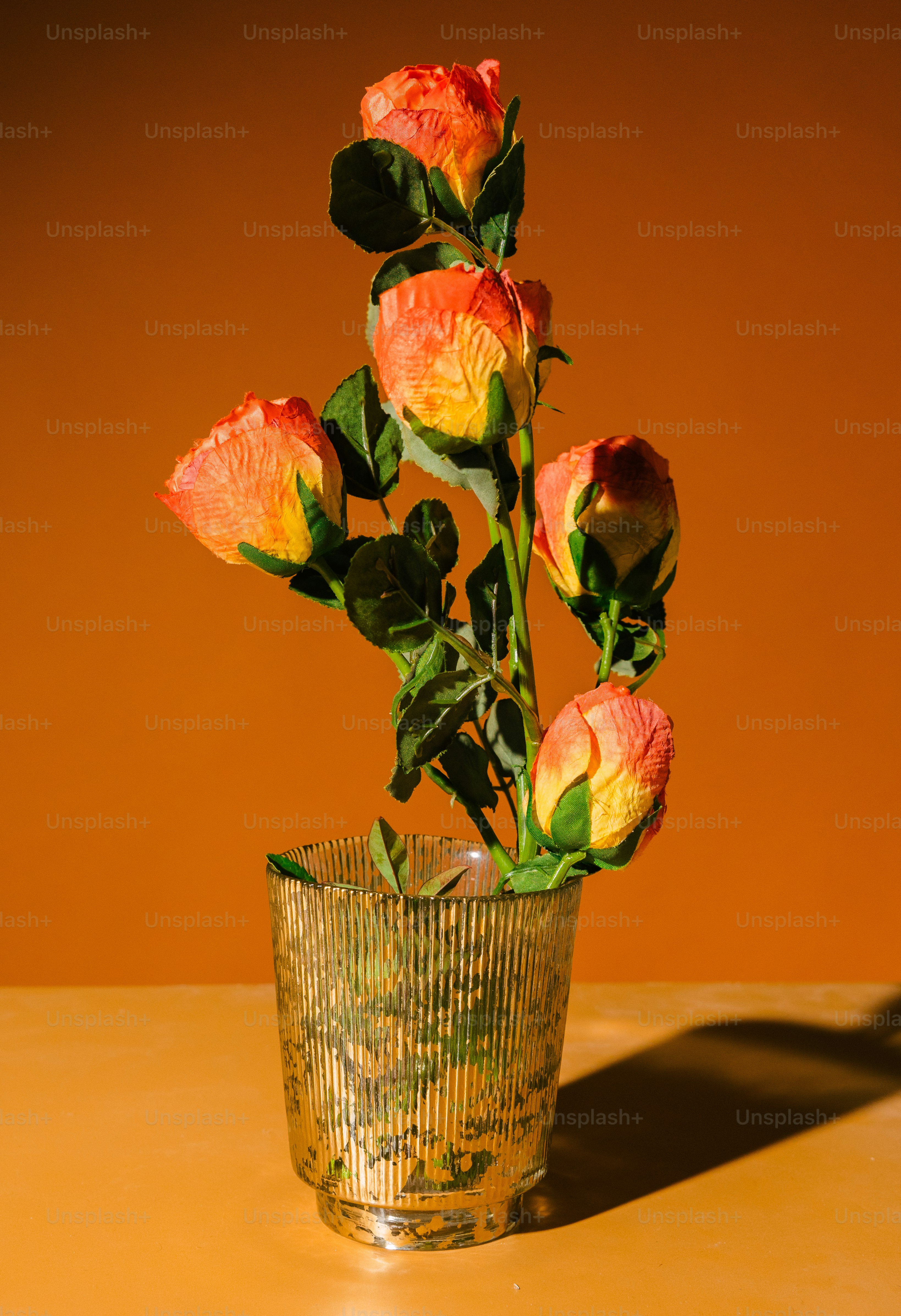 Un jarrón de vidrio lleno de flores encima de una mesa
