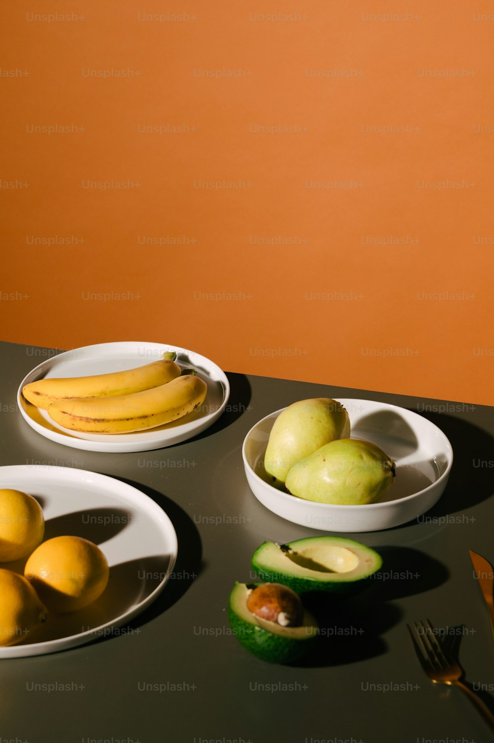 a table topped with plates of fruit and a bowl of bananas