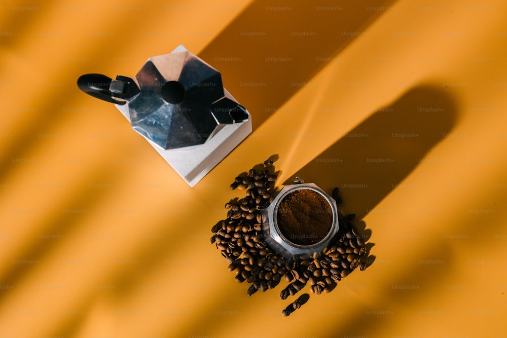 una taza de café junto a un molinillo y granos de café