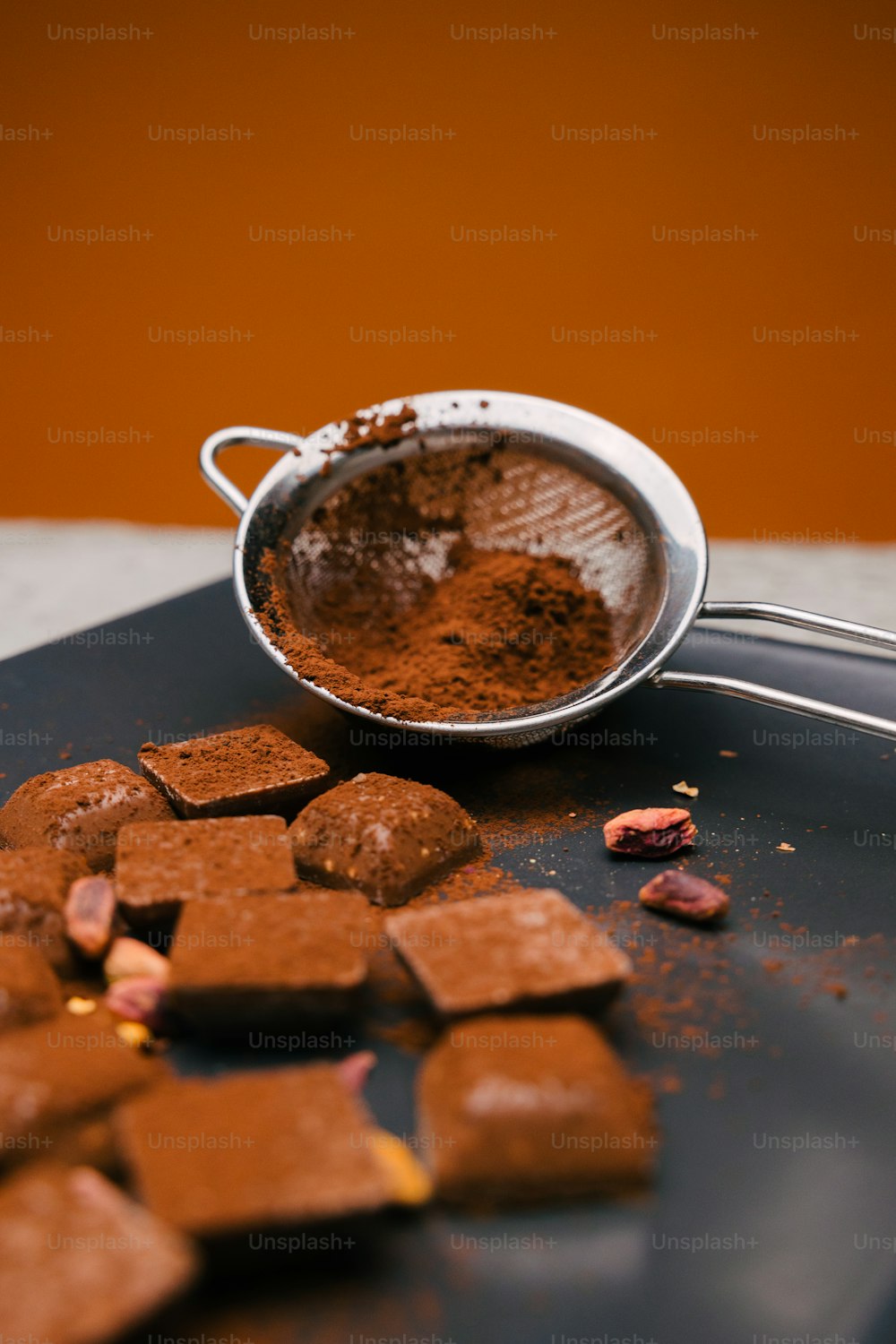 eine Metallschüssel gefüllt mit Schokoladenstücken neben einer Kugel Kakao