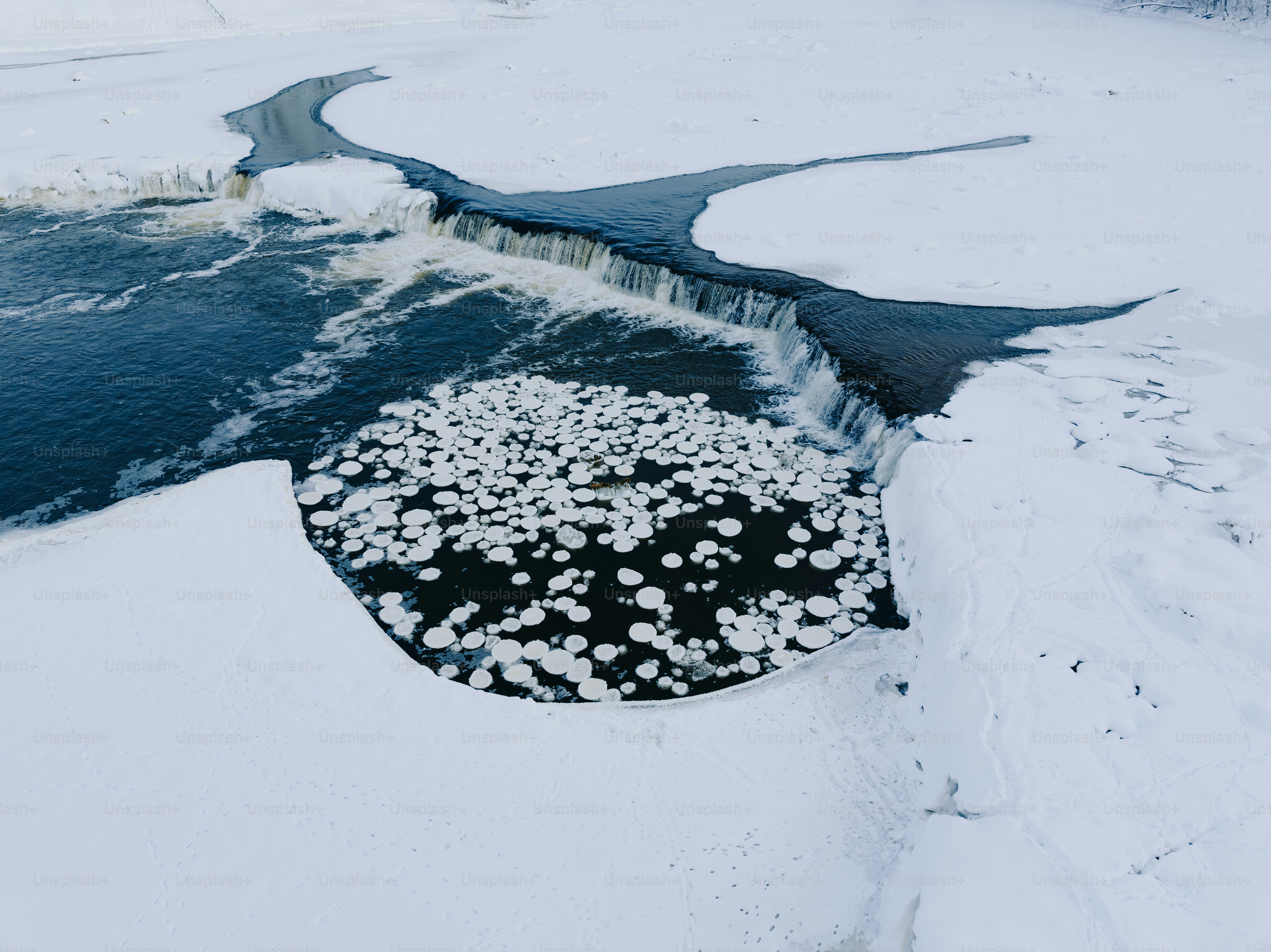 a frozen river with a small waterfall in the middle of it