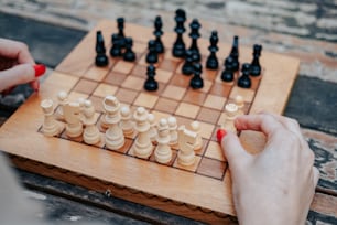 uma pessoa que joga um jogo de xadrez em um tabuleiro de madeira