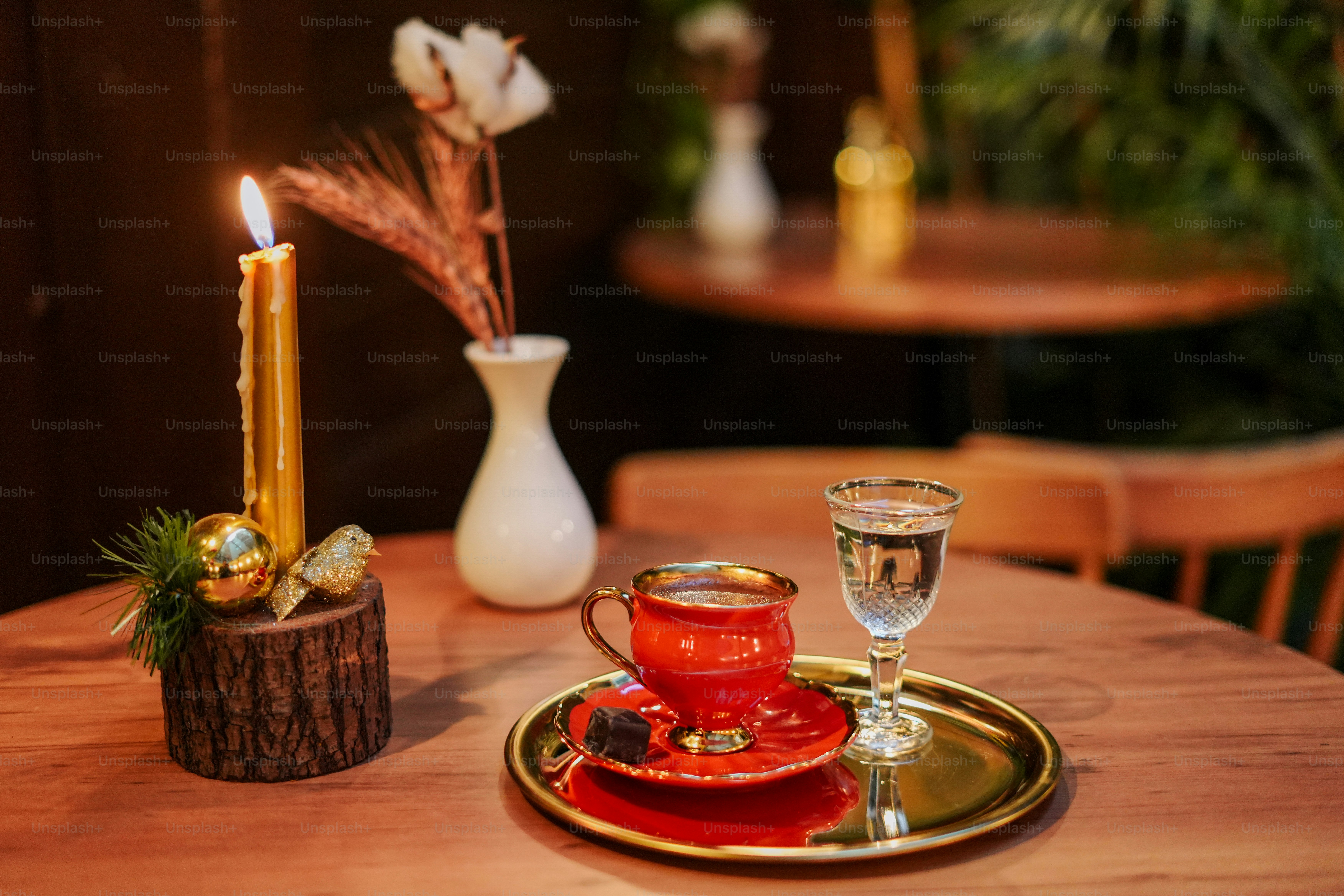 a wooden table topped with a red cup and saucer