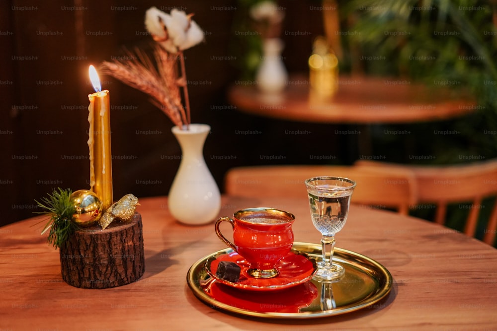 a wooden table topped with a red cup and saucer