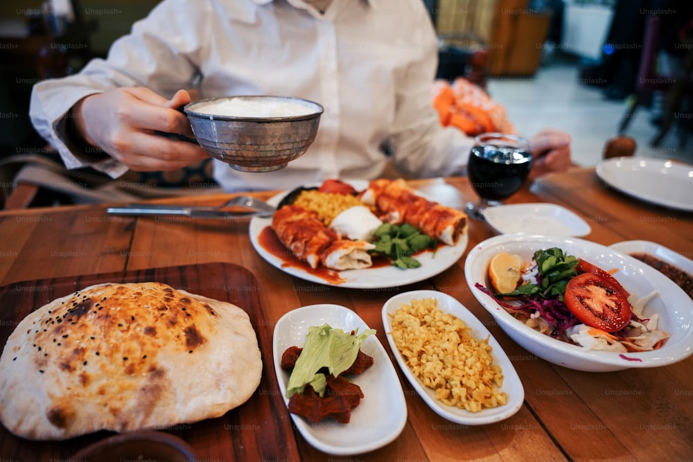 una persona seduta a un tavolo con piatti di cibo
