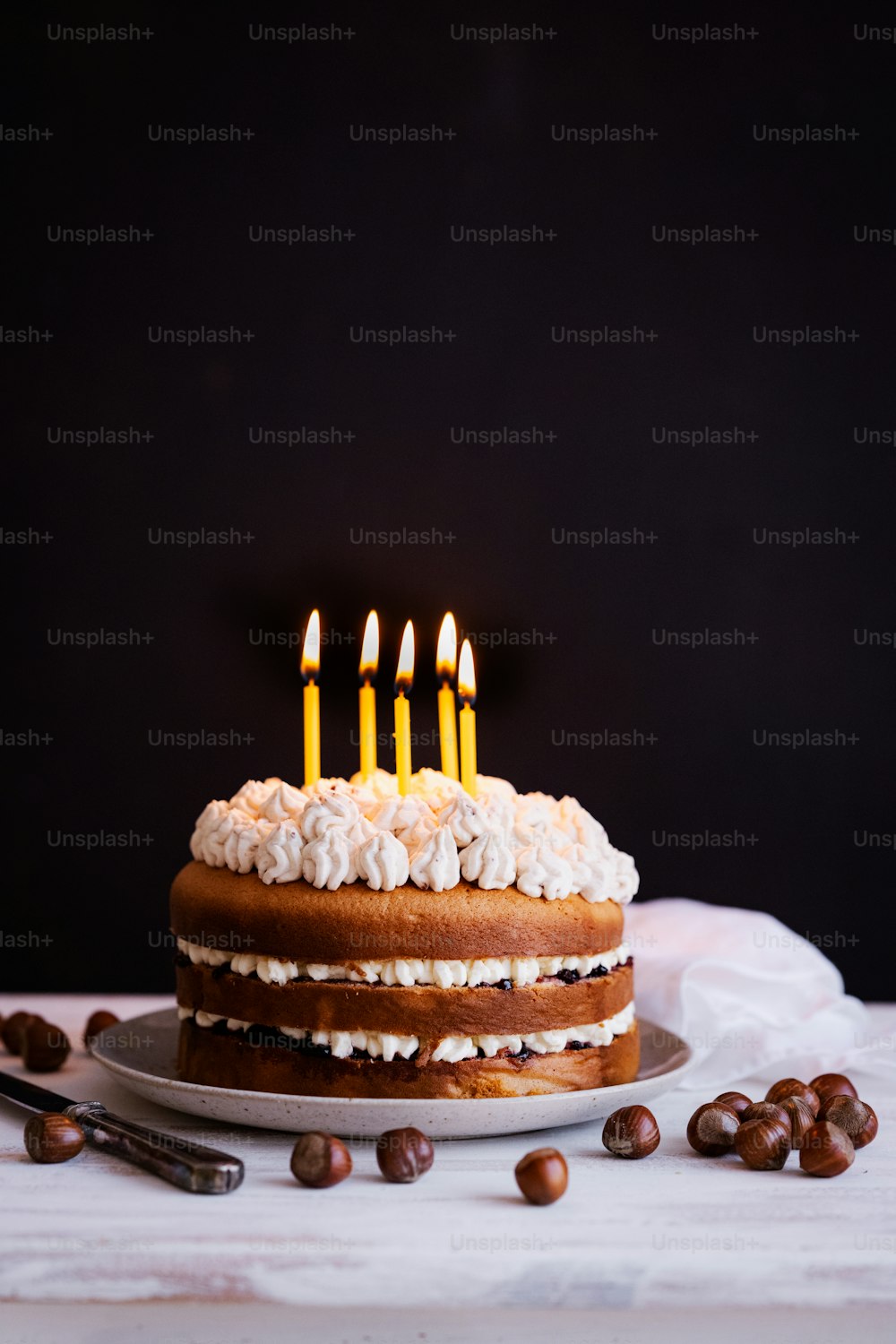 um bolo de aniversário com velas acesas sentado em uma mesa