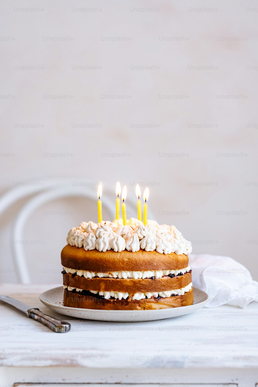 白いフロスティングと火のともったキャンドルのケーキ