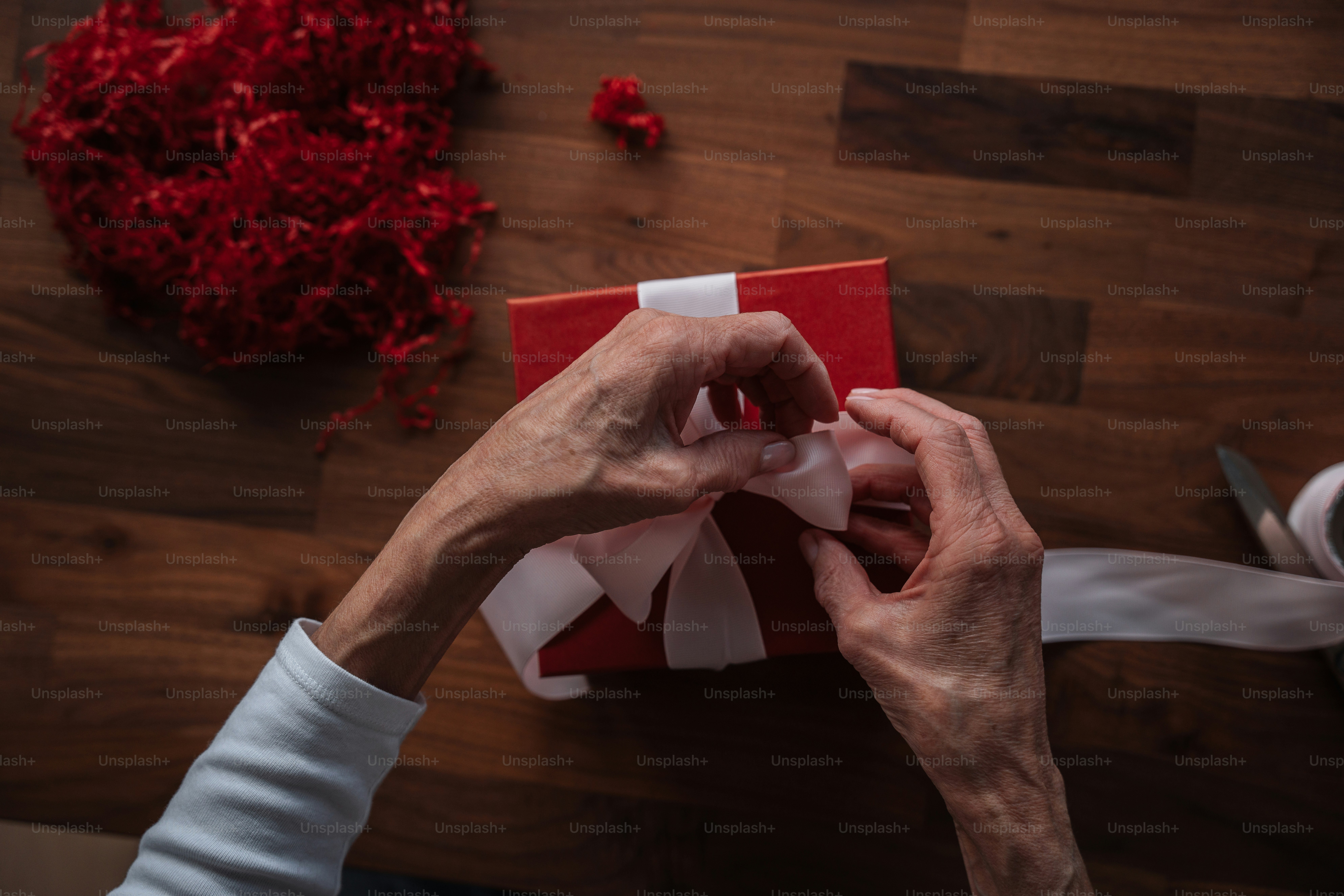 A person wrapping a red gift with white ribbon photo Valentines day
