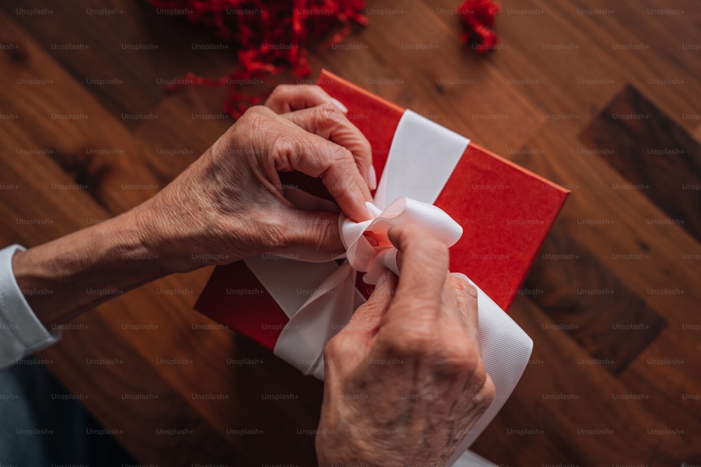 uma pessoa envolvendo um presente vermelho e branco