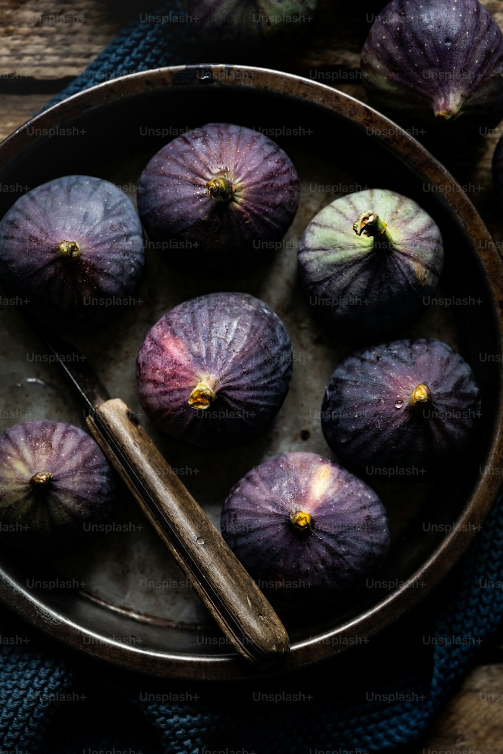 a bowl filled with purple figs on top of a table