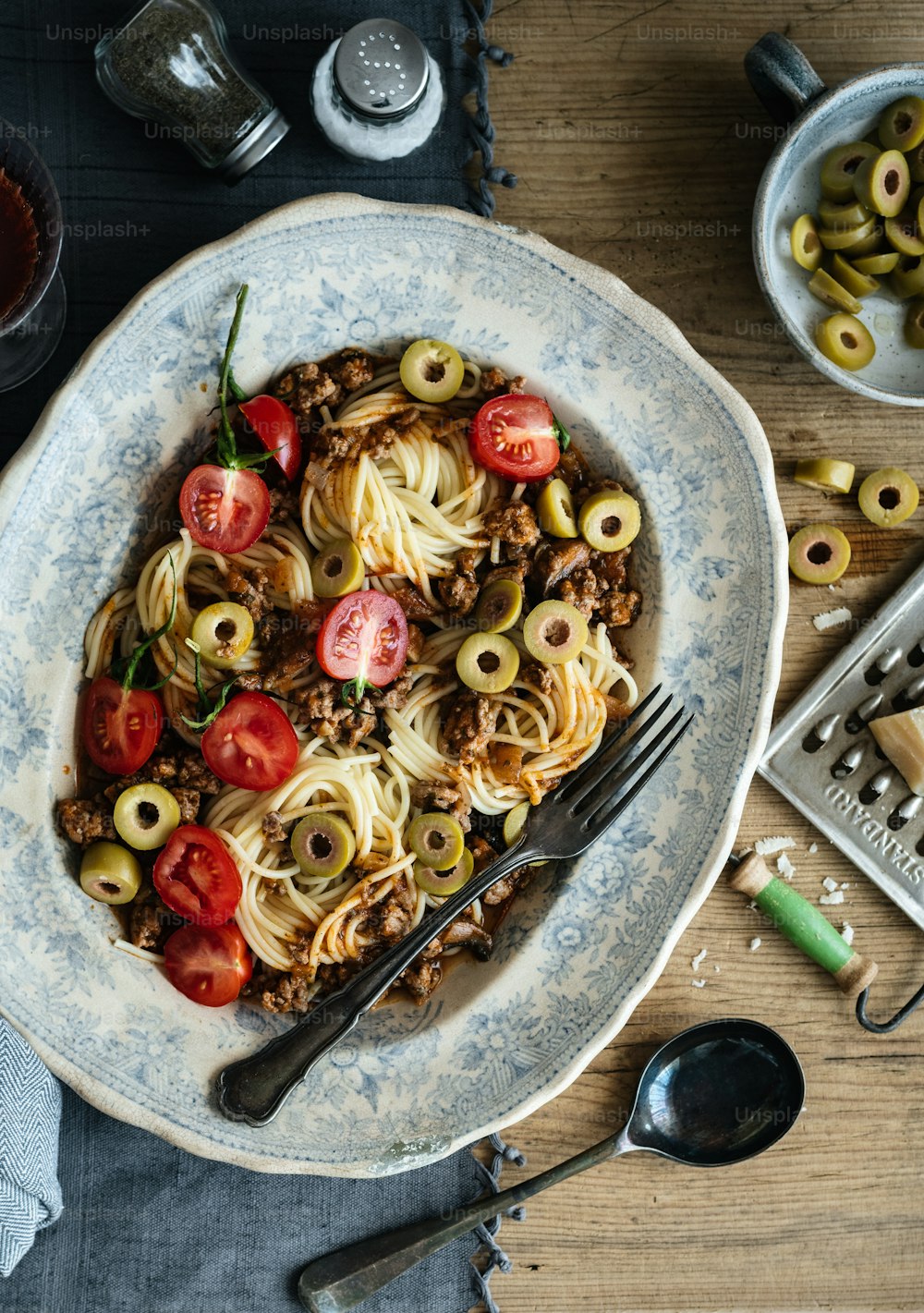 a plate of pasta with olives and tomatoes