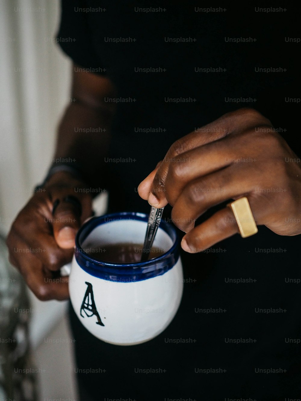 a person holding a coffee mug with a pen in it