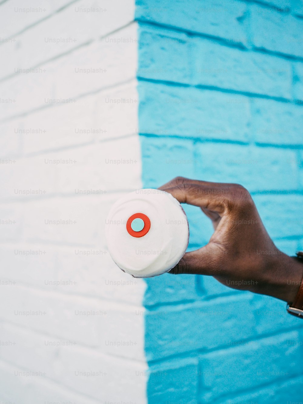 a person holding a white frisbee in front of a blue brick wall
