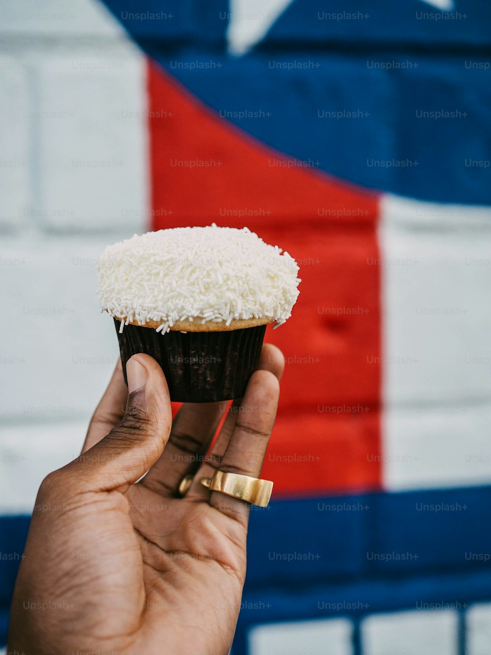 une main tenant un cupcake avec un glaçage blanc
