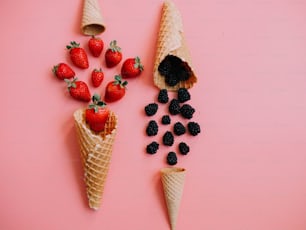 two cones of ice cream with strawberries and blackberries