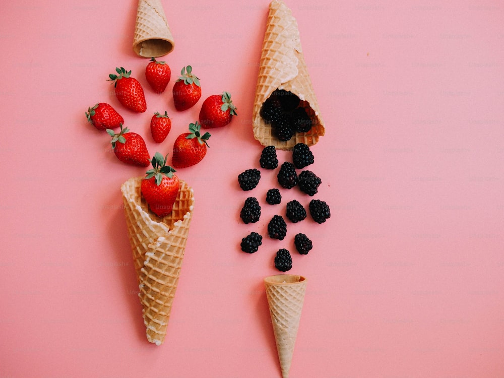 two cones of ice cream with strawberries and blackberries