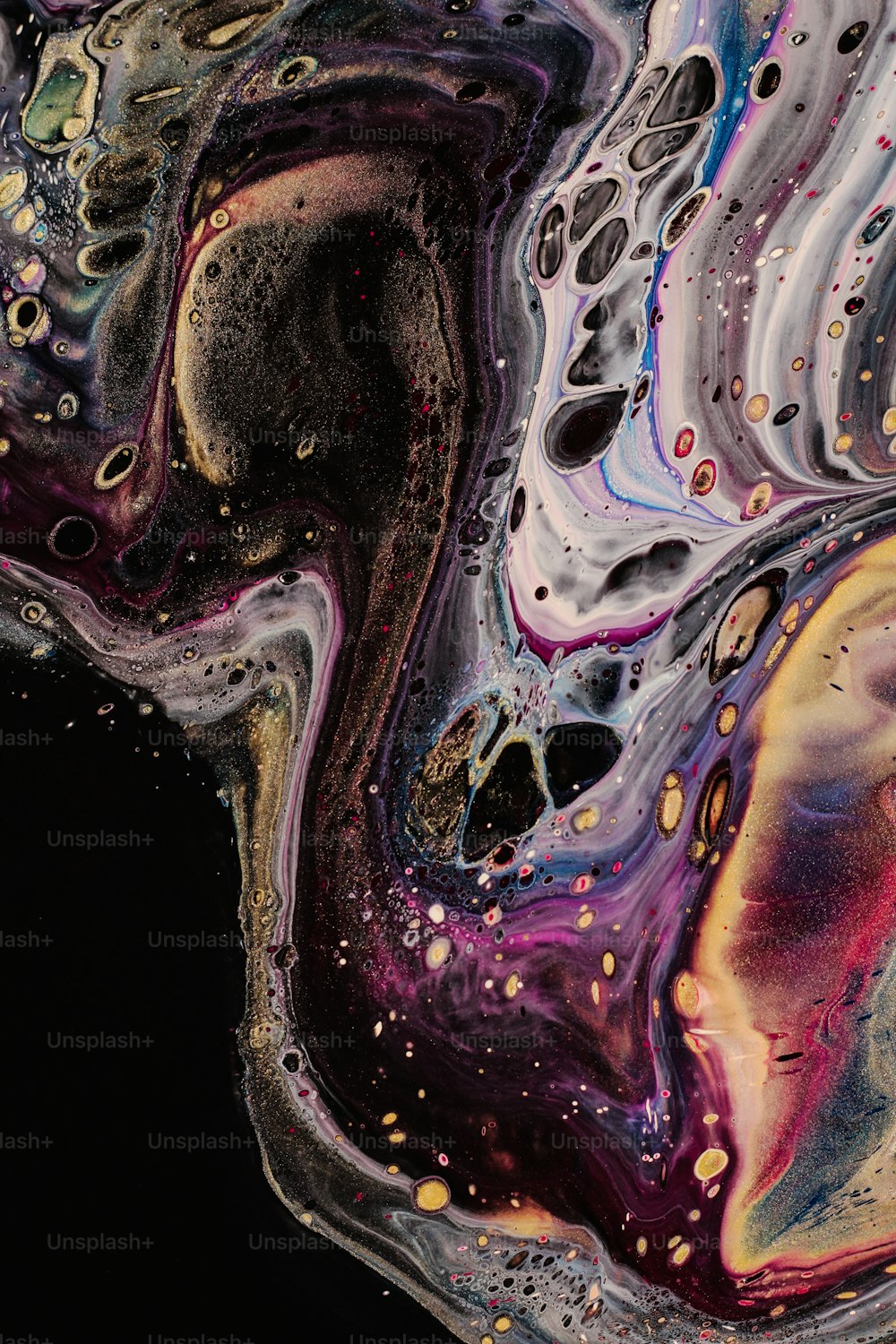 a close up of a black background with colorful liquid