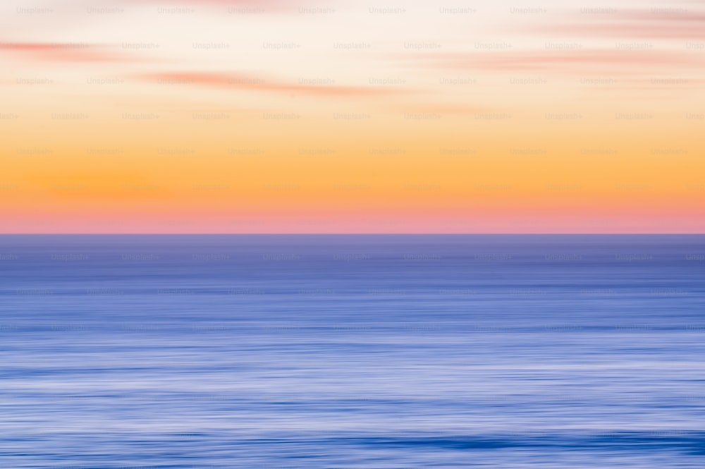 uma foto borrada do oceano ao pôr do sol