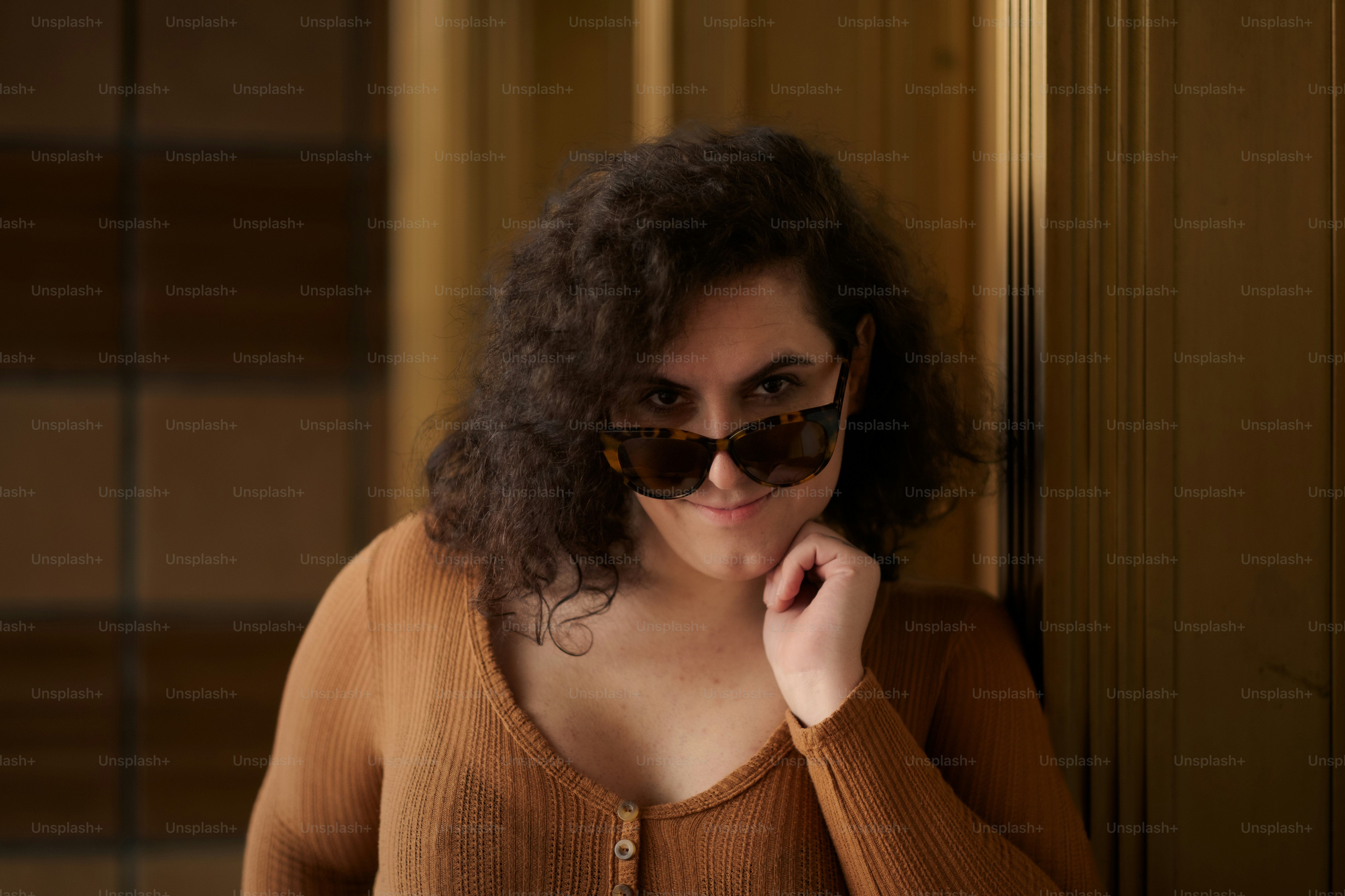 a woman wearing sunglasses leaning against a wall