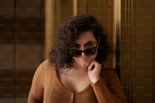 a woman wearing sunglasses leaning against a wall