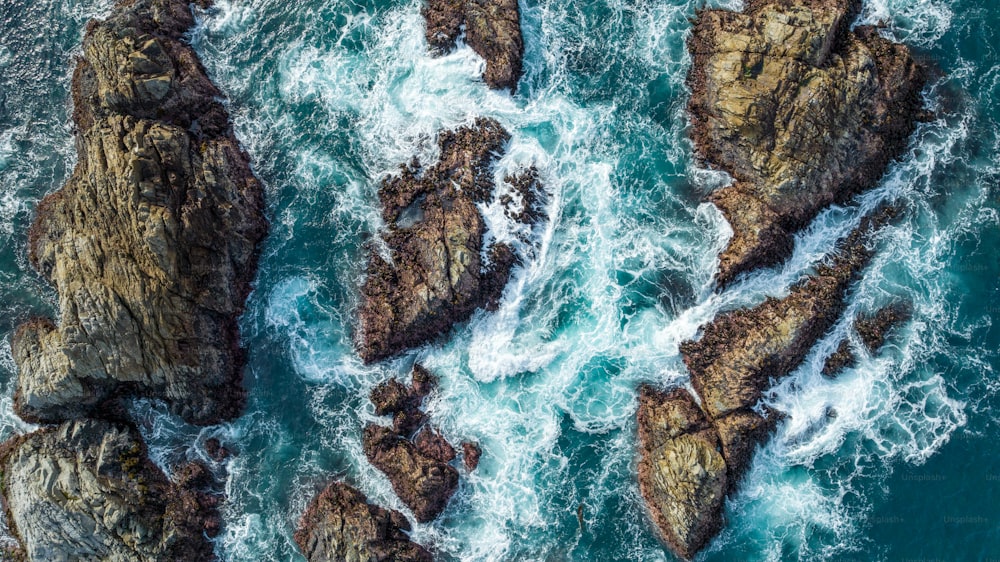 an aerial view of the ocean and rocks