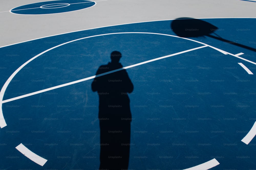 a shadow of a person on a basketball court