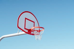 a red and white basketball hoop with a clear blue sky in the background
