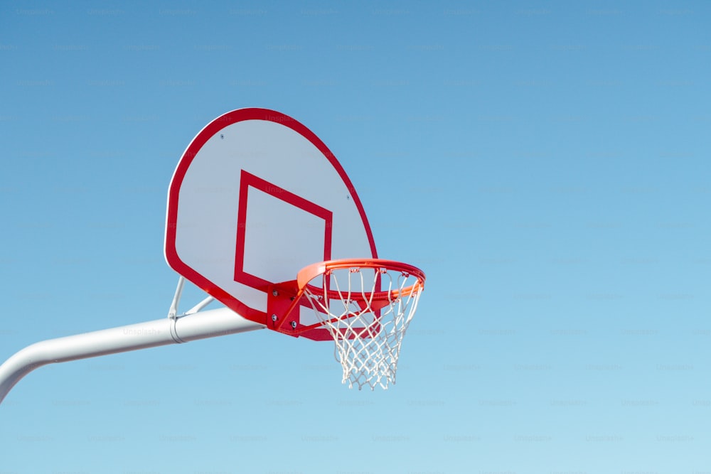 a red and white basketball hoop with a clear blue sky in the background