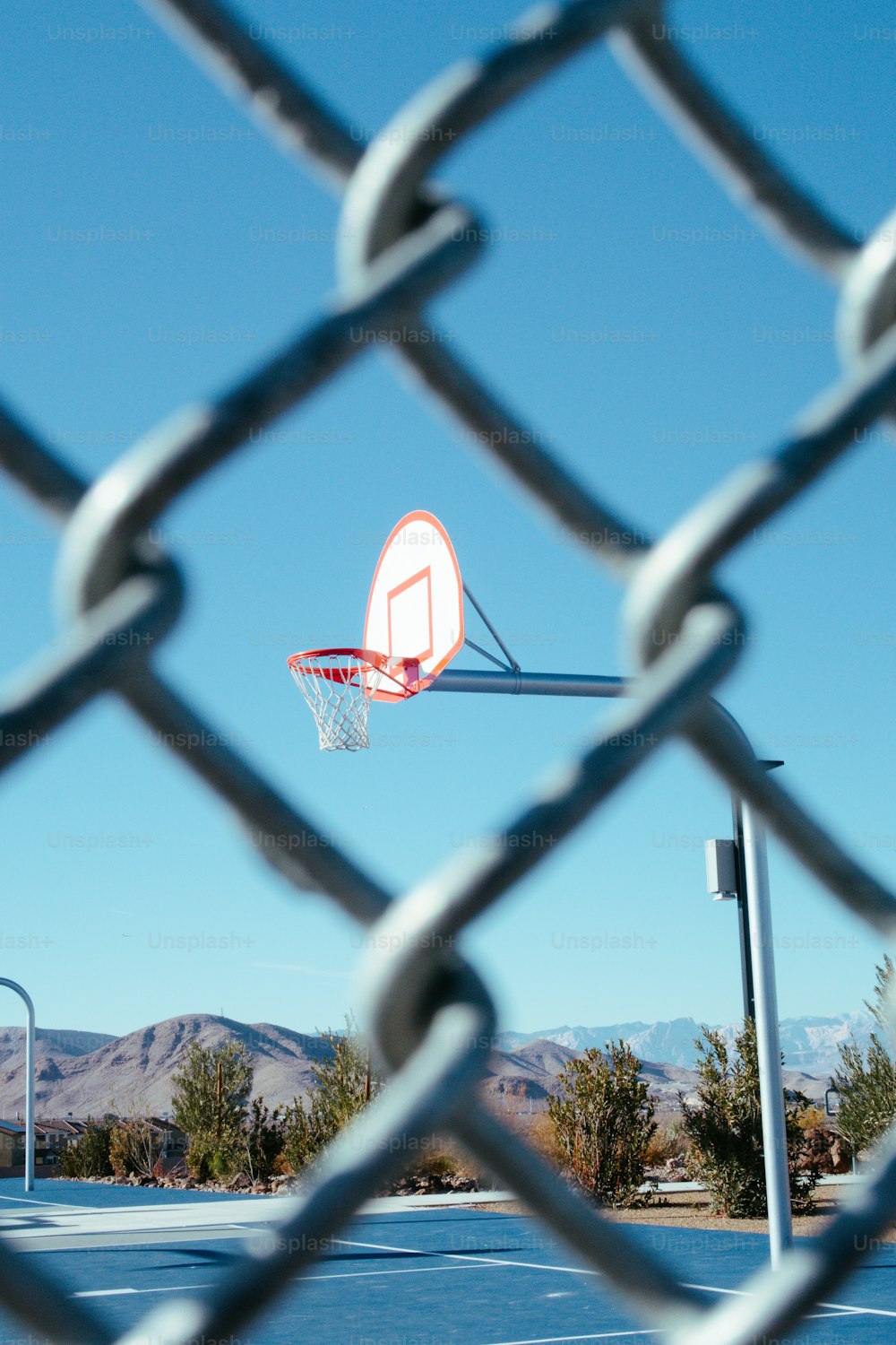 a basketball hoop is seen through a chain link fence