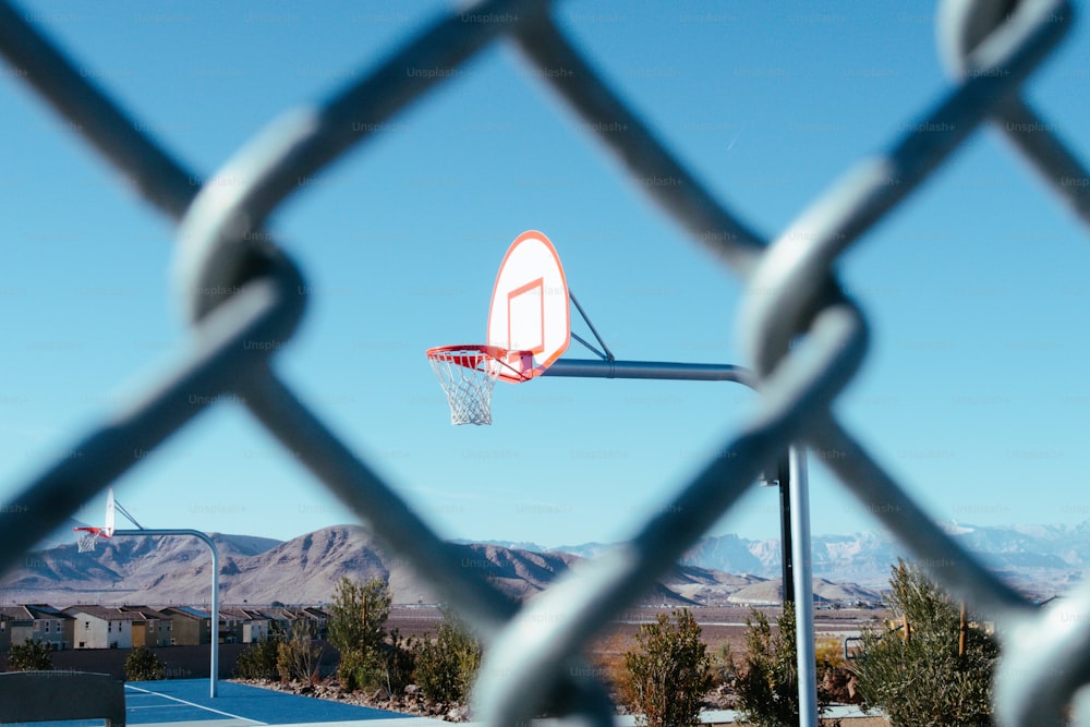 a basketball hoop is seen through a chain link fence