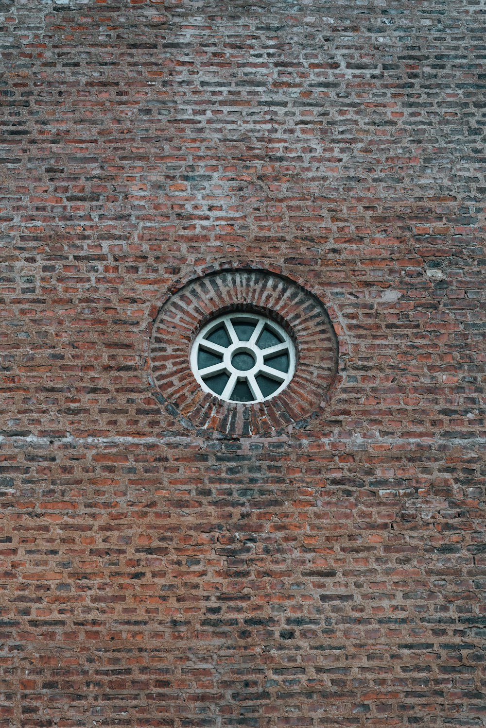 Una ventana redonda en una pared de ladrillo