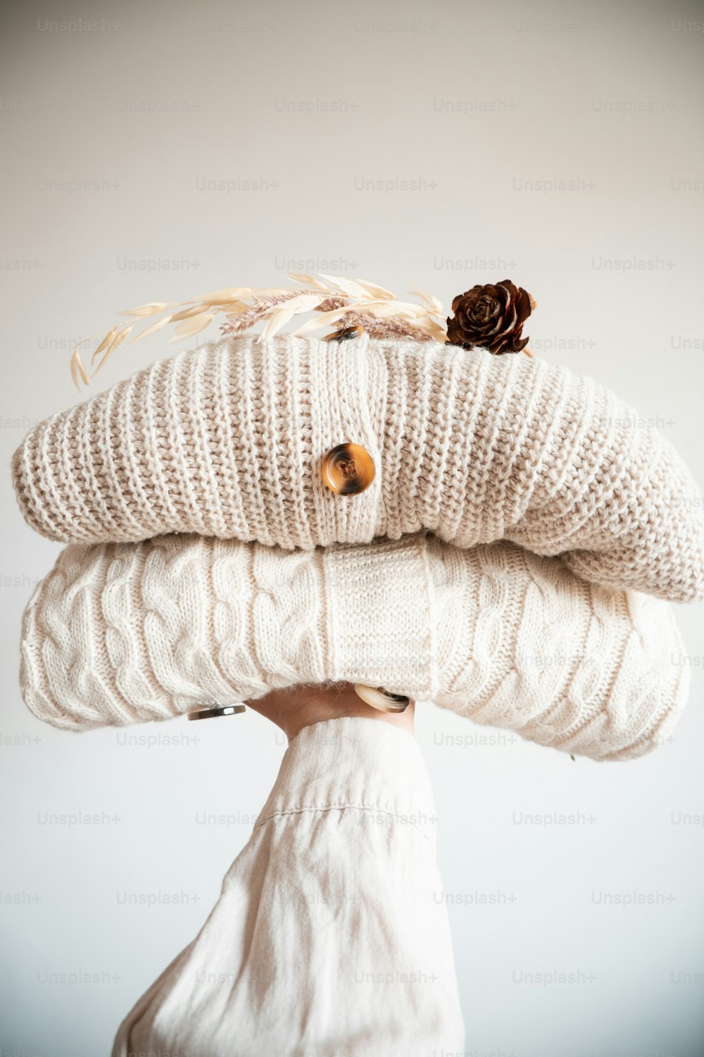 a person holding two sweaters on top of each other