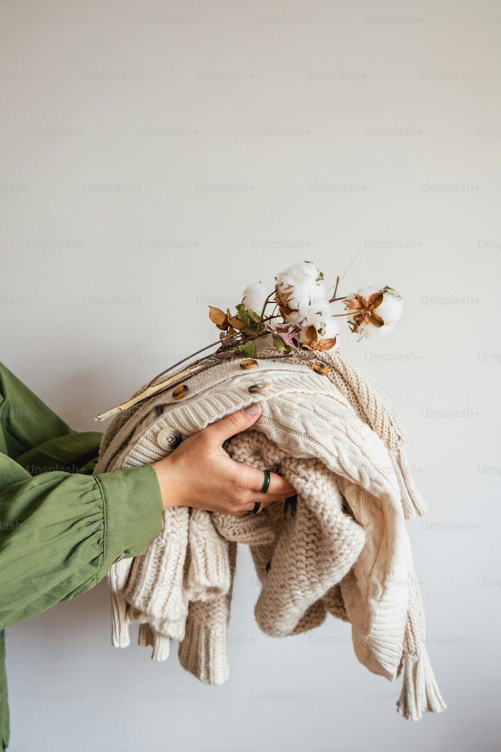 a person holding a pile of sweaters and flowers
