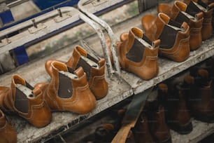 a row of brown shoes sitting on top of a metal shelf