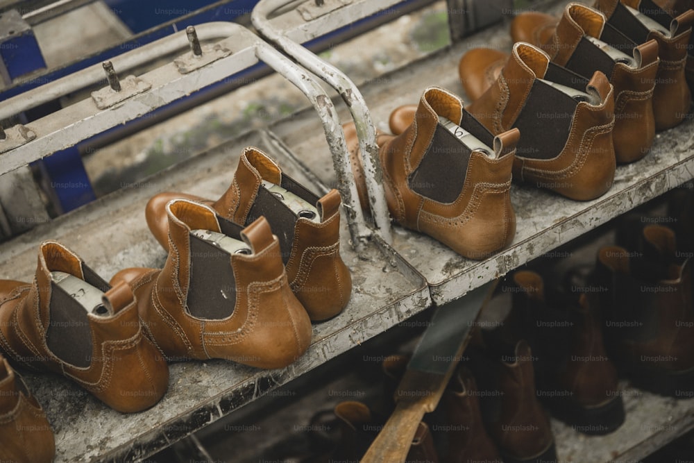 una fila di scarpe marroni sedute sopra uno scaffale di metallo