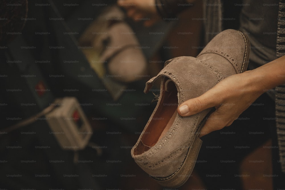 une personne tenant une paire de chaussures à la main