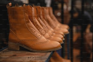 a row of brown boots sitting on top of a wooden table