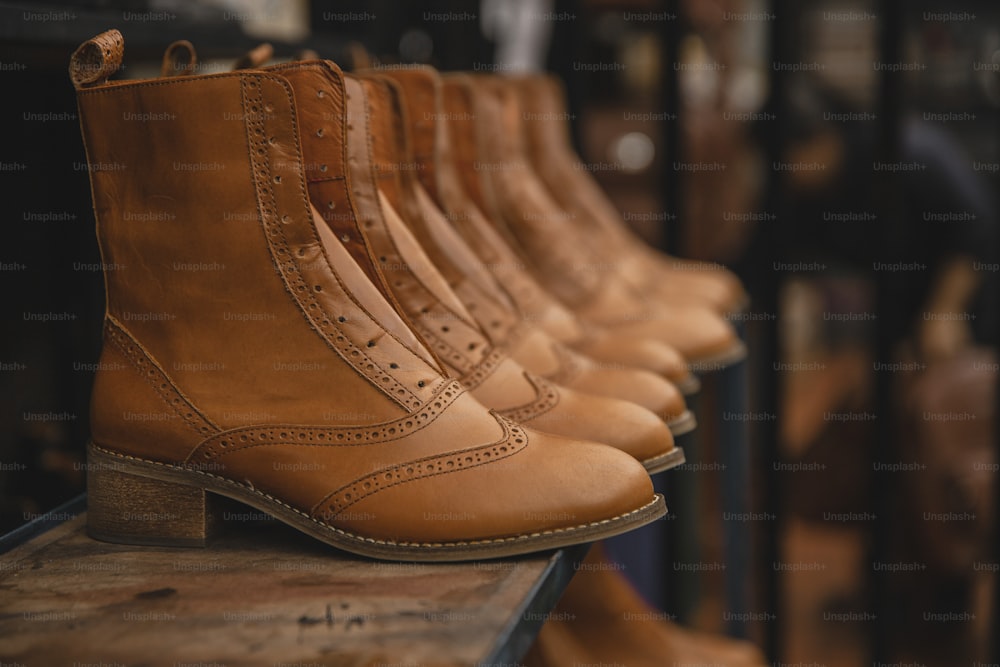 a row of brown boots sitting on top of a wooden table