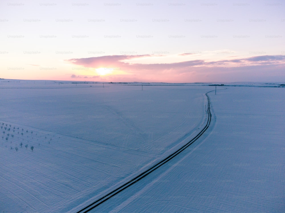 a snow covered field with tracks in the snow